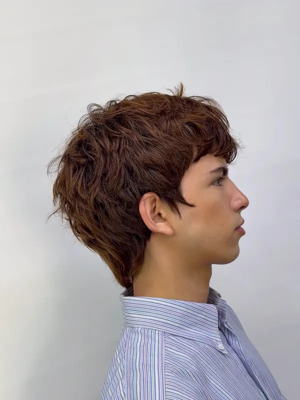 Corte con textura y flequillo en cabello castaño, de perfil