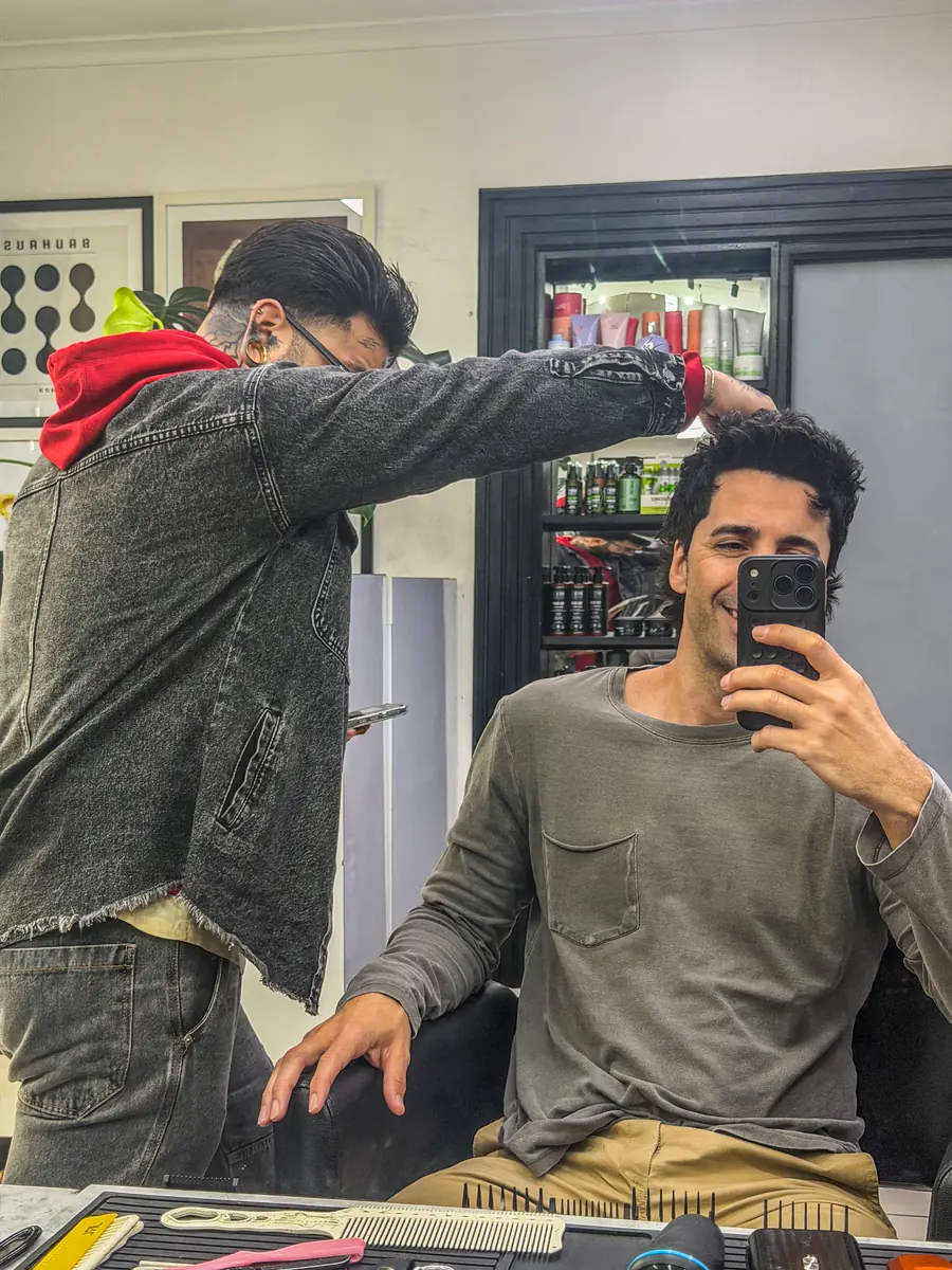 Barbero peinando a un cliente sentado en el sillón