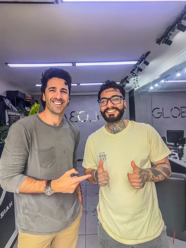 Dos clientes sonriendo dentro del estudio, con el letrero GLOBAL al fondo