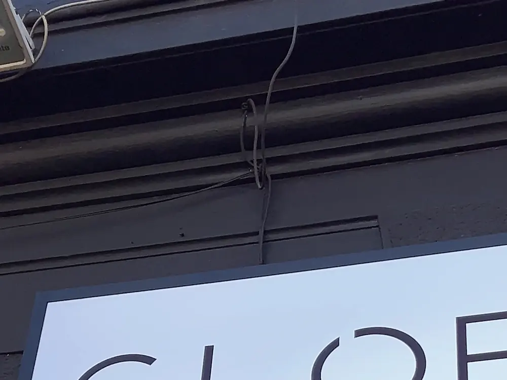 Letrero blanco con el logotipo GLOBAL Hair Studio sobre la entrada