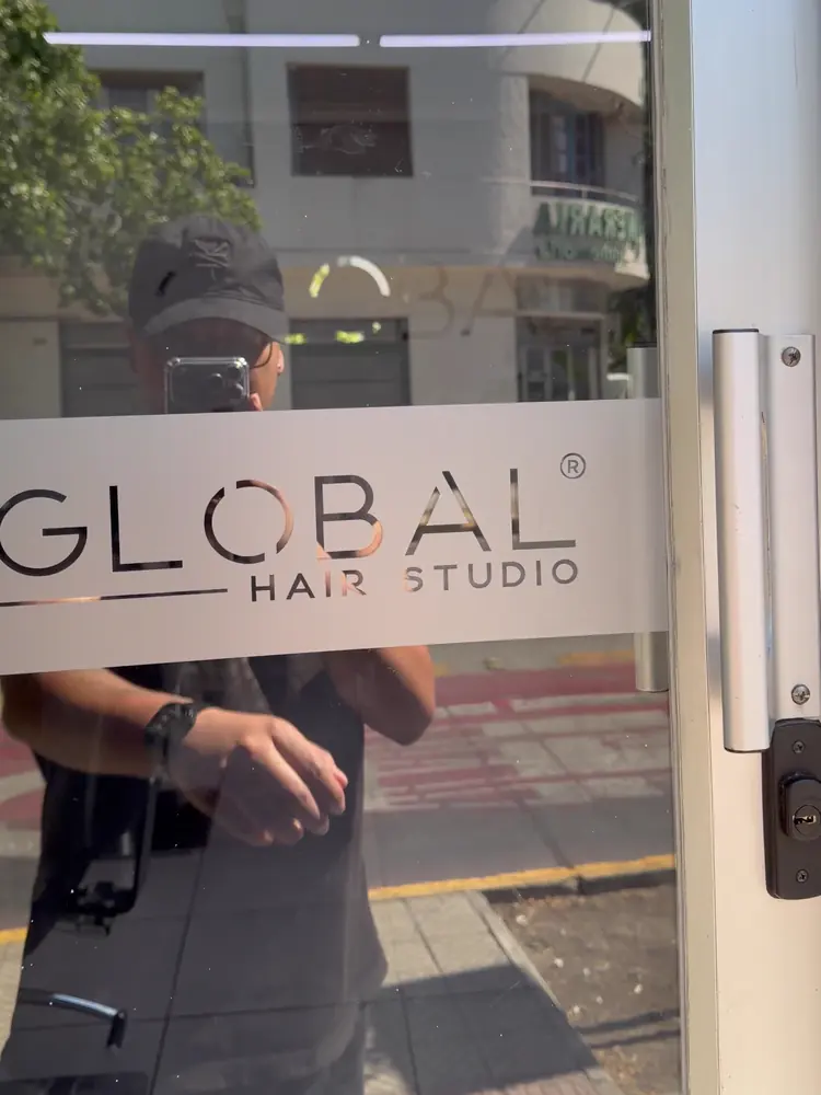 Puerta de vidrio con el logotipo GLOBAL Hair Studio en vinilo
